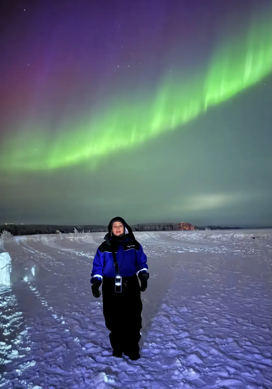 Viajero con traje térmico bajo una aurora intensa